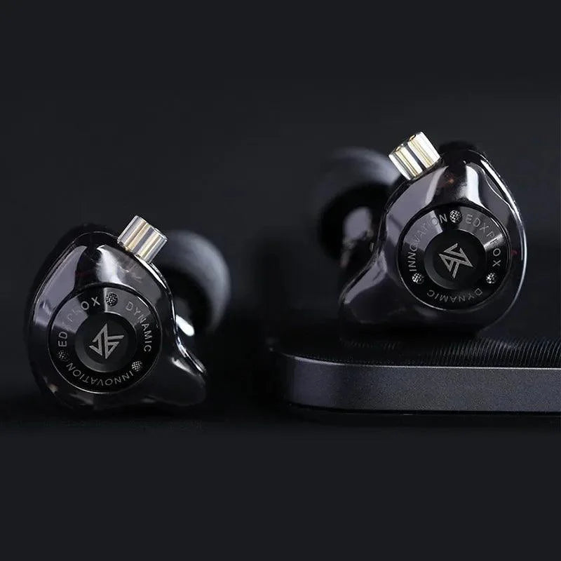 Close-up shot of Black KZ EDX Pro X earphones on a dark surface, highlighting star‑style faceplate and cable wrap.