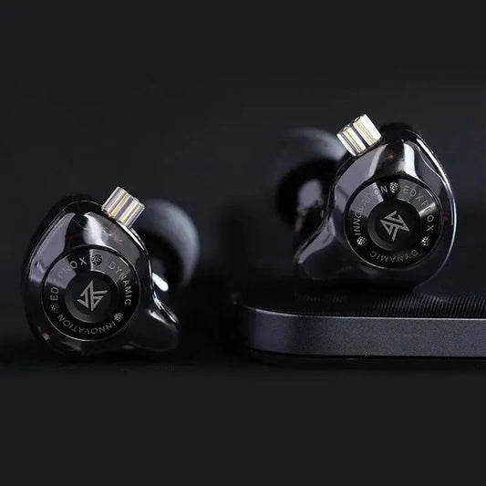 Close-up shot of Black KZ EDX Pro X earphones on a dark surface, highlighting star‑style faceplate and cable wrap.